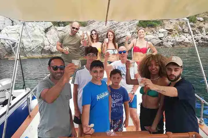 A group of guests on board in front of the rocks of Isola Bella
