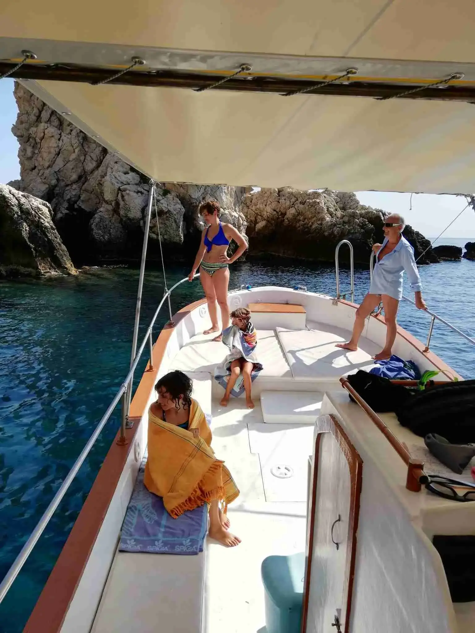 Guests relaxing on deck under the sunshade near the cliffs of Taormina