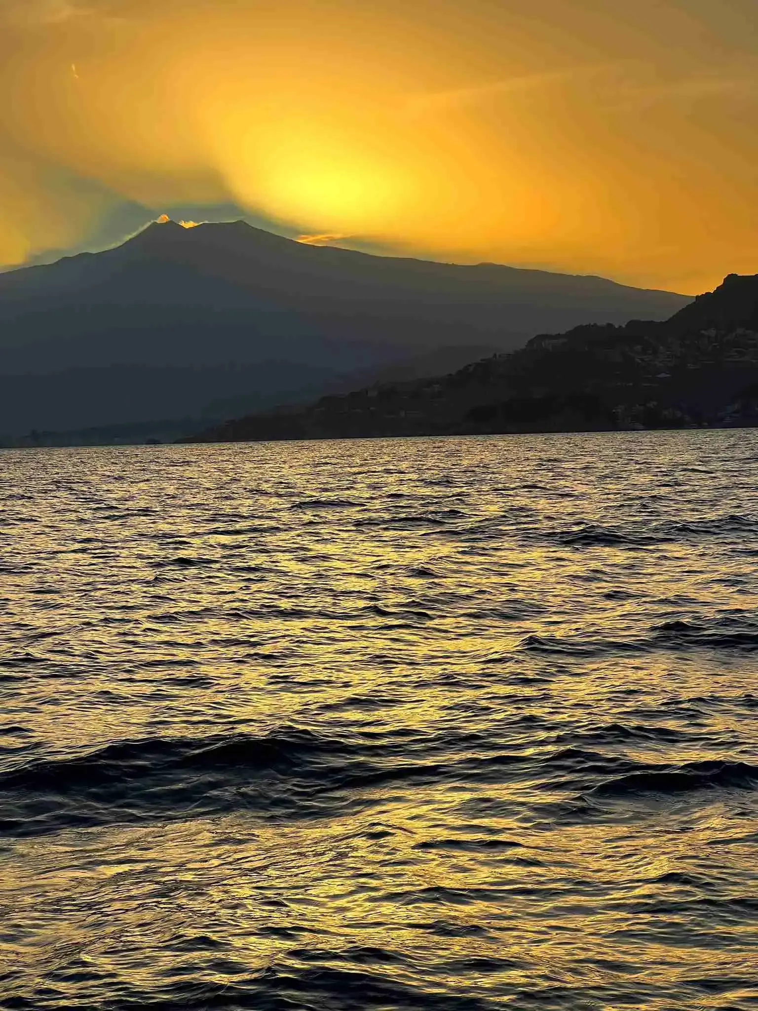 Golden sunset behind Mount Etna, seen from the sea